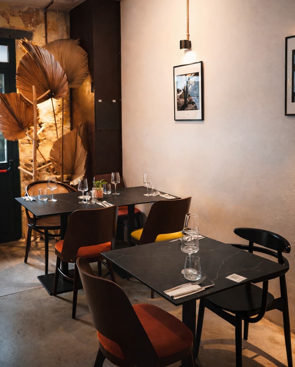 La salle du Vieux Comptoir : murs patinés, palmes séchées, tables en pierre noire dressées